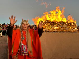 A vibrant traditional ceremony in Tiwanaku, Bolivia, featuring a man in traditional attire near a bonfire.